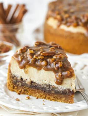 A slice of pecan pie cheesecake eon a plate with a fork.