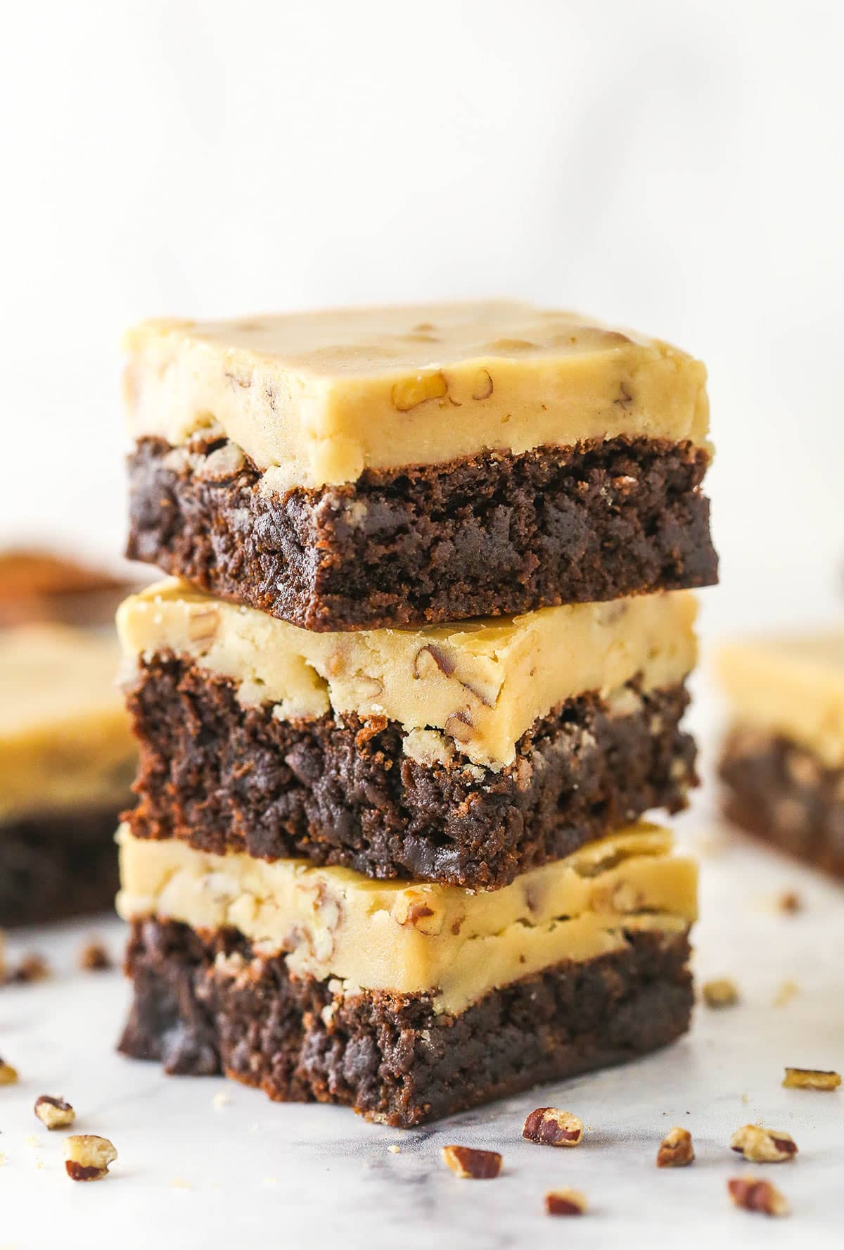 A stack of 3 Praline Pecan Brownies on a marble surface.
