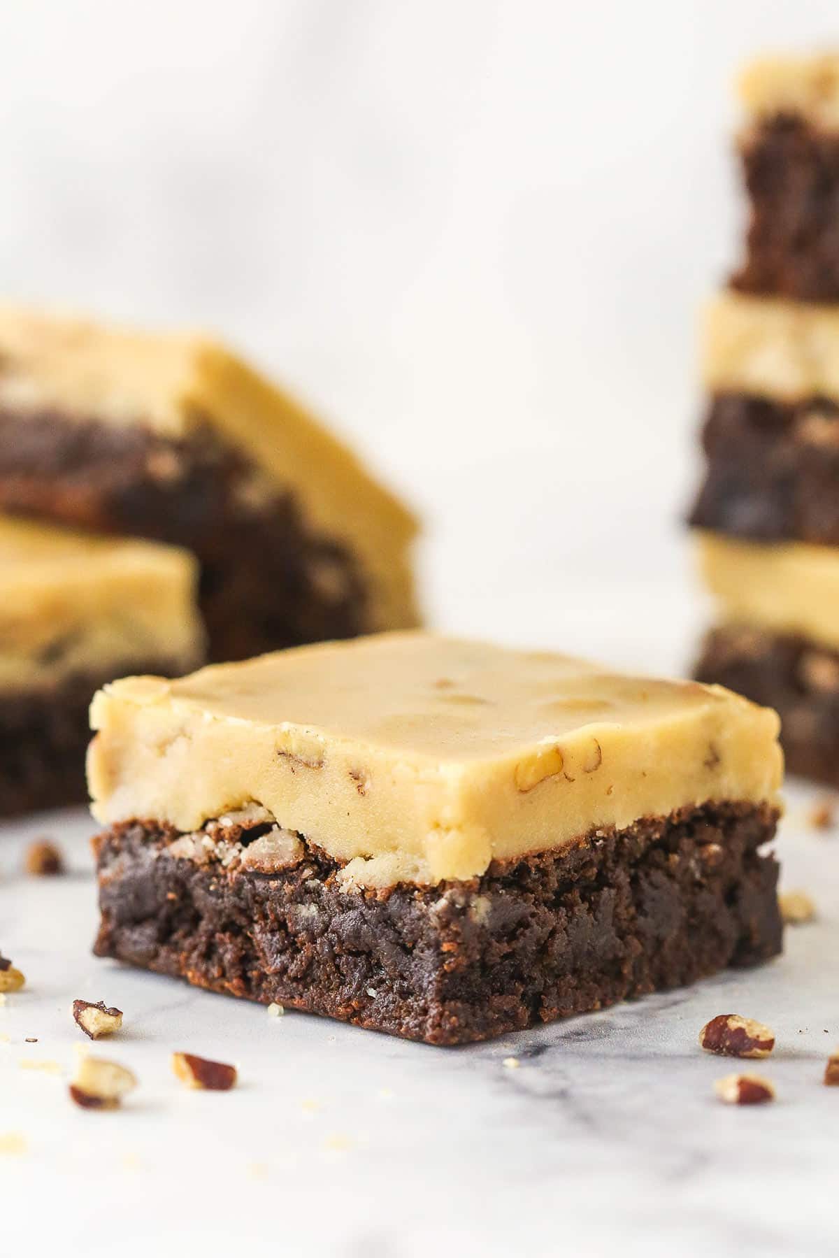 1 Praline Pecan Brownie on a marble surface with more brownies in the background.