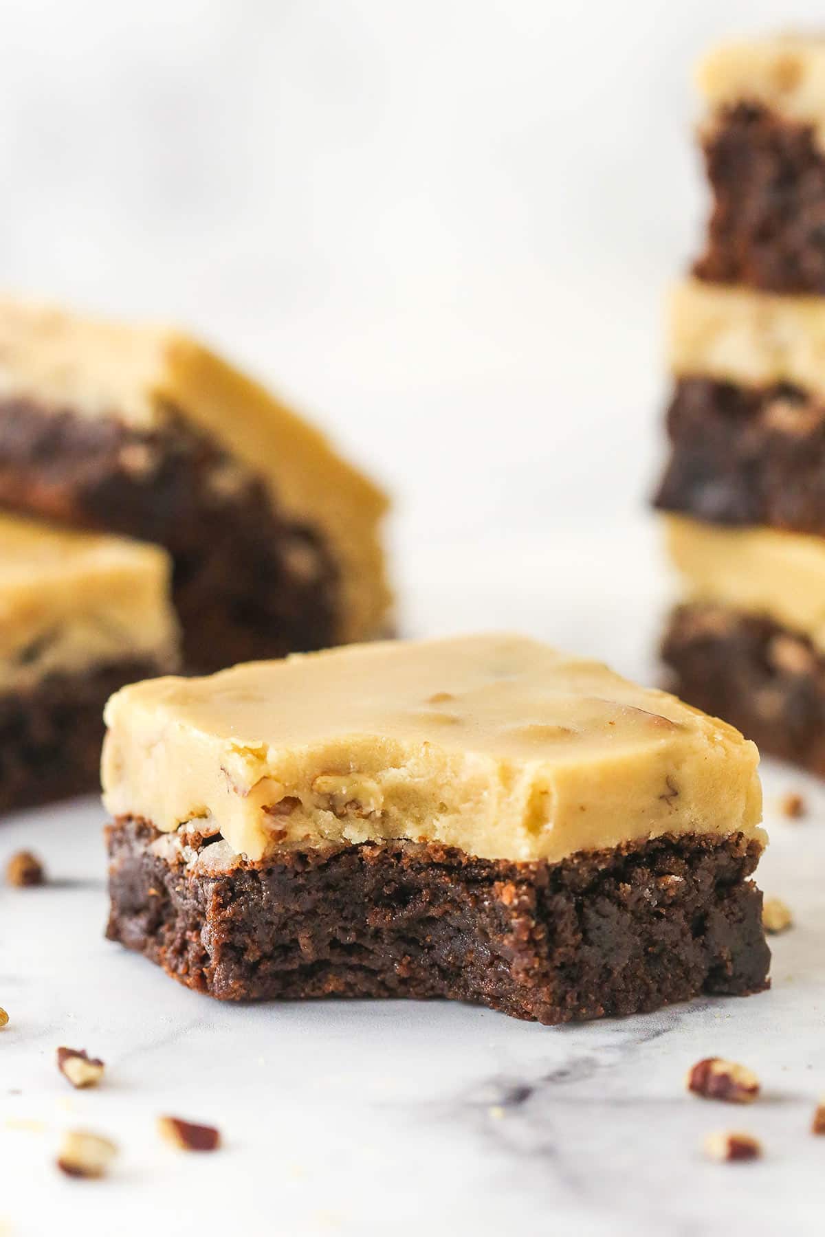 A Praline Pecan Brownie with a bite removed and more brownies in the background.