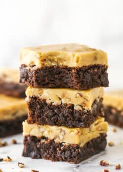 A stack of 3 Praline Pecan Brownies with a bite removed from top brownie.