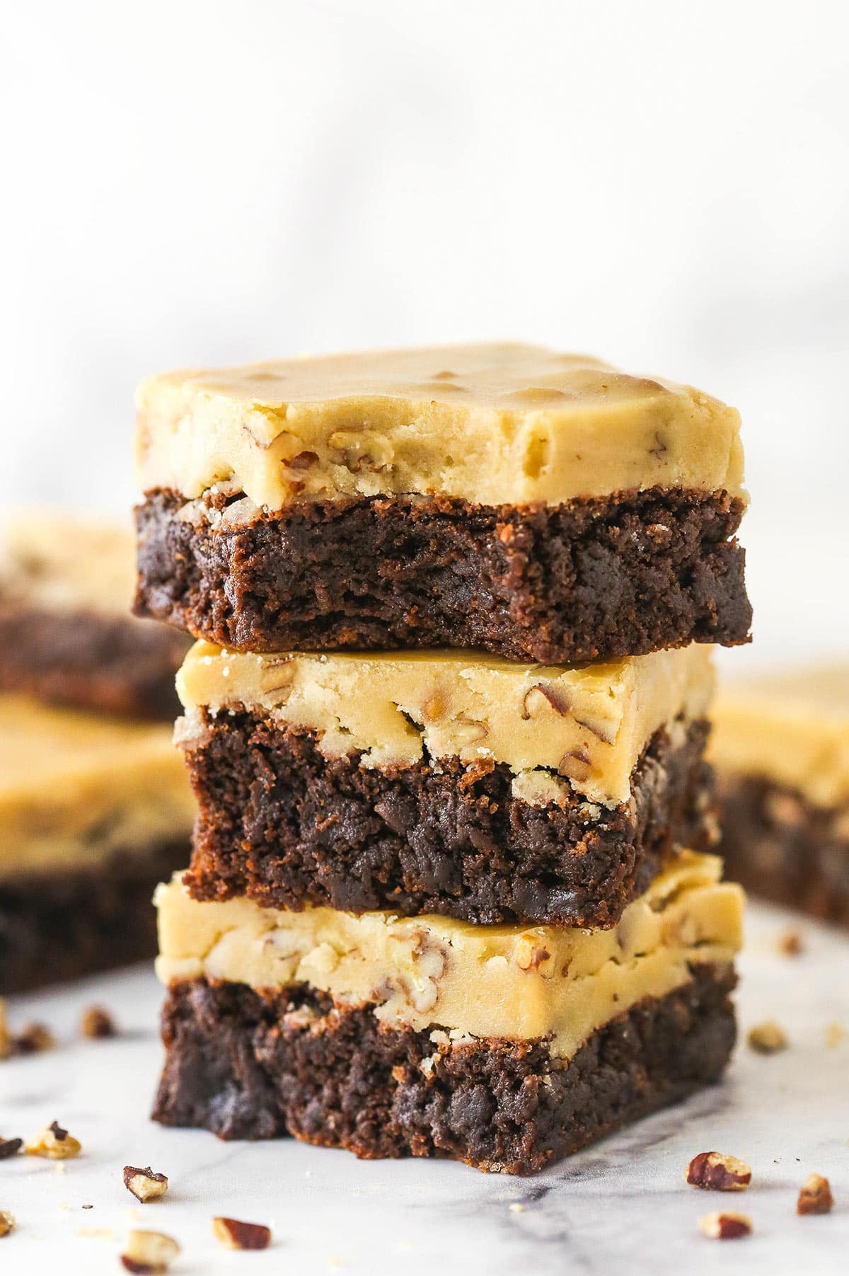 A stack of 3 Praline Pecan Brownies with a bite removed from top brownie.