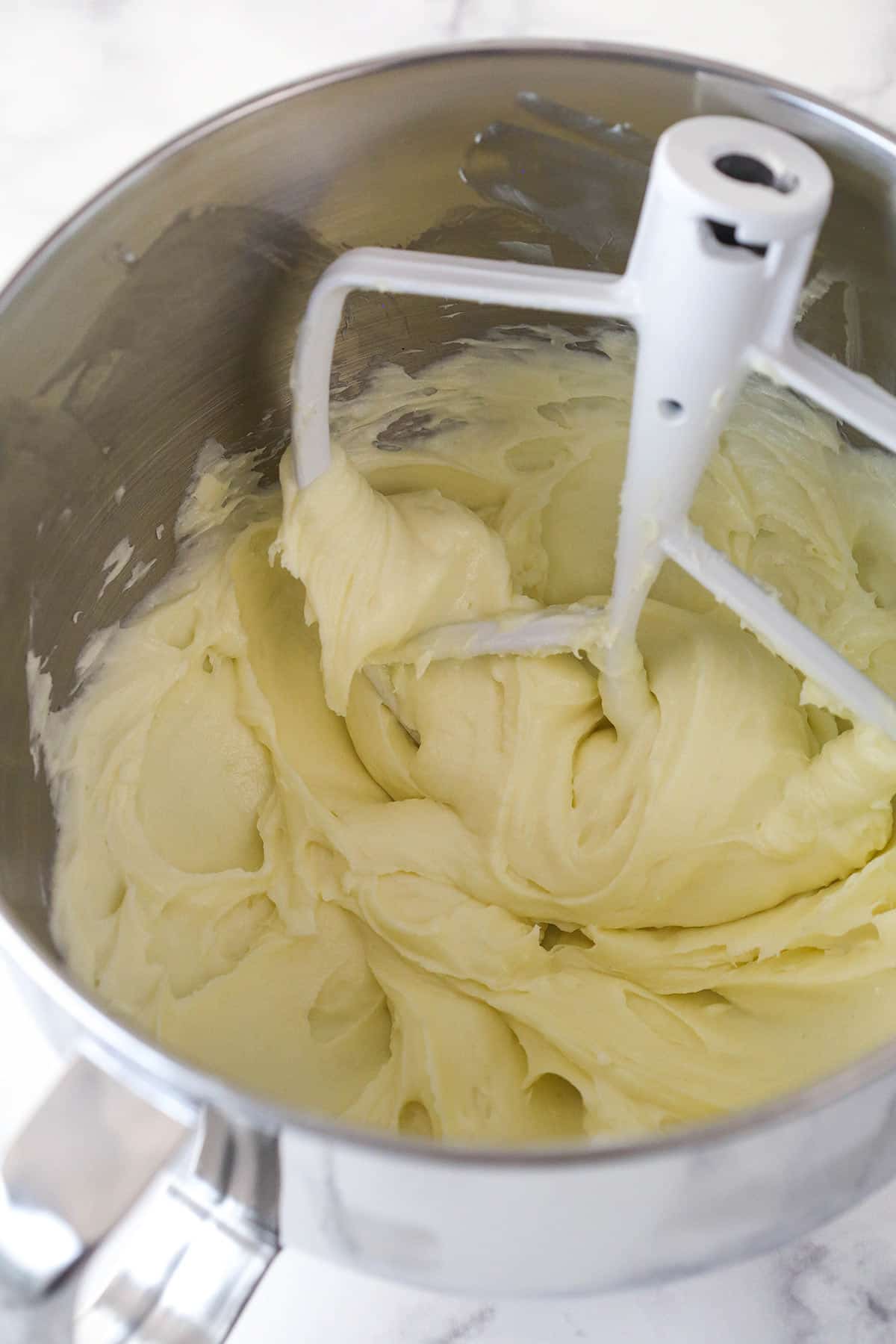 Mixing together cream cheese, sugar, and flour for cheesecake.
