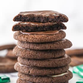 A stack of Andes mint chocolate cookies. The cookie on top is broken in half.