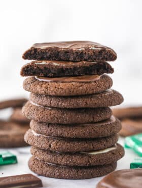 A stack of Andes mint chocolate cookies. The cookie on top is broken in half.