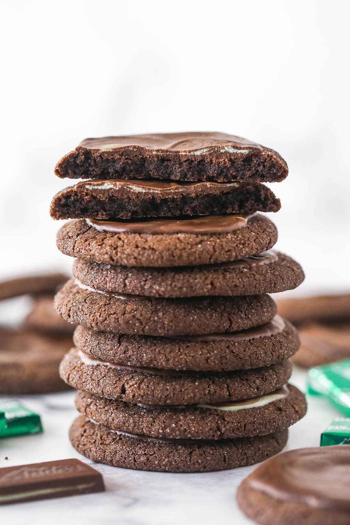 Andes mint cookies are made up of soft, chewy chocolate sugar cookies spread with melted Andes mint chocolates. So good! A stack of Andes mint chocolate cookies. The cookie on top is broken in half.
