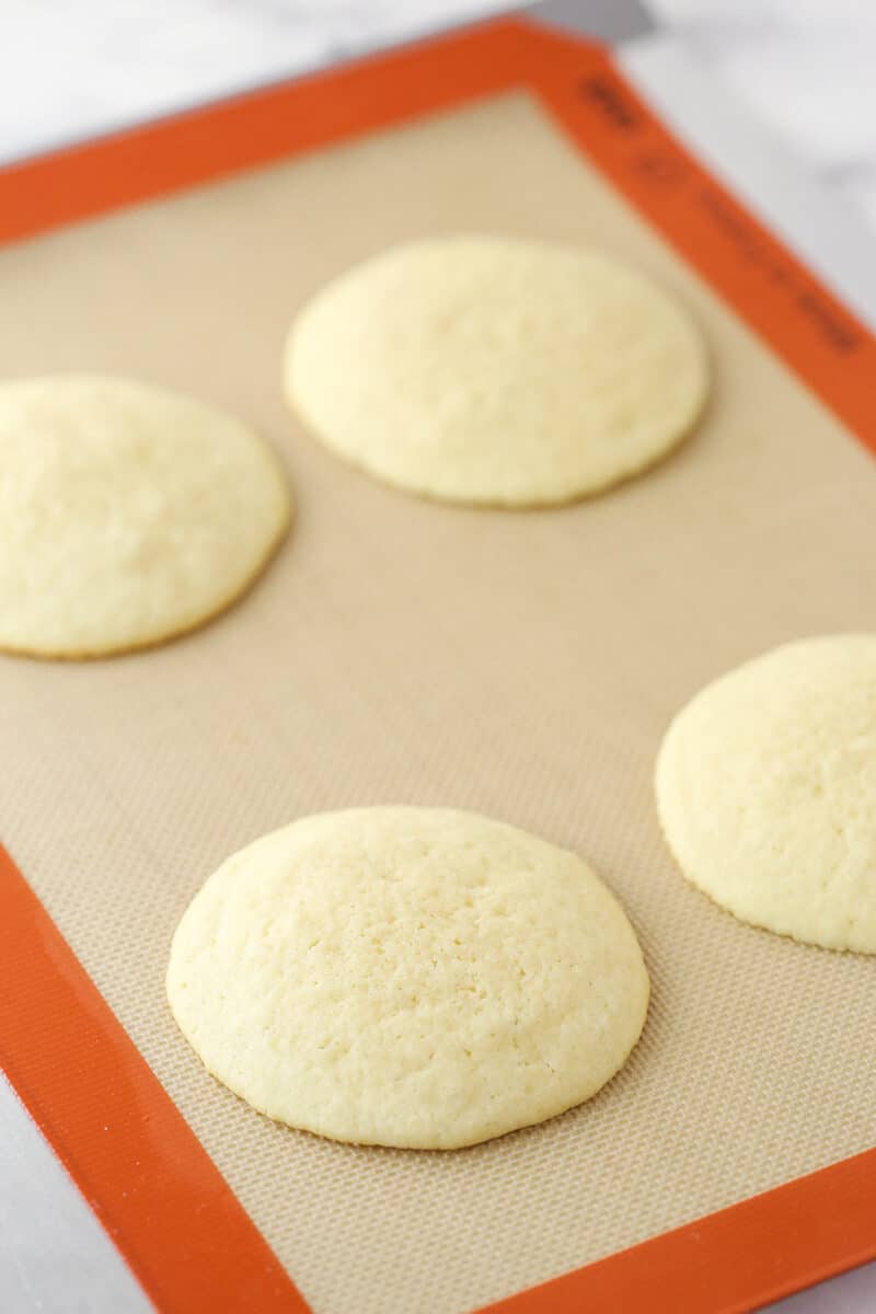 Half moon cookies on a silicon baking mat before being frosted.