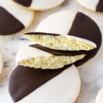 Black and white cookies on a marble surface. One cookie is broken in half.