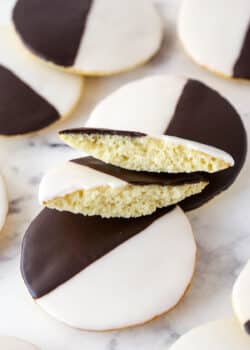 Black and white cookies on a marble surface. One cookie is broken in half.