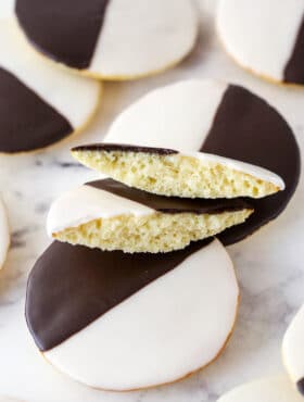 Black and white cookies on a marble surface. One cookie is broken in half.