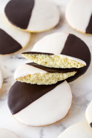 Black and white cookies on a marble surface. One cookie is broken in half.