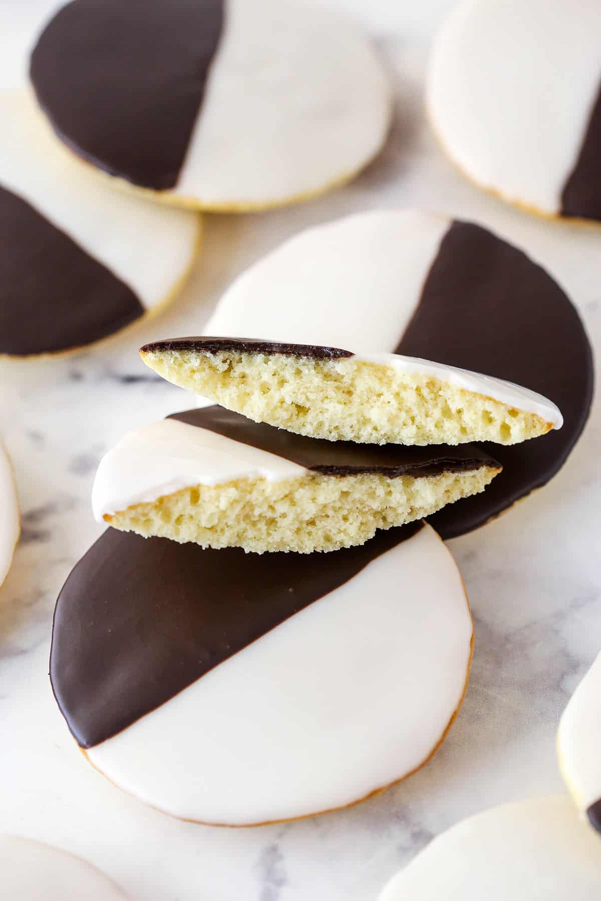 Black and white cookies on a marble surface. One cookie is broken in half.