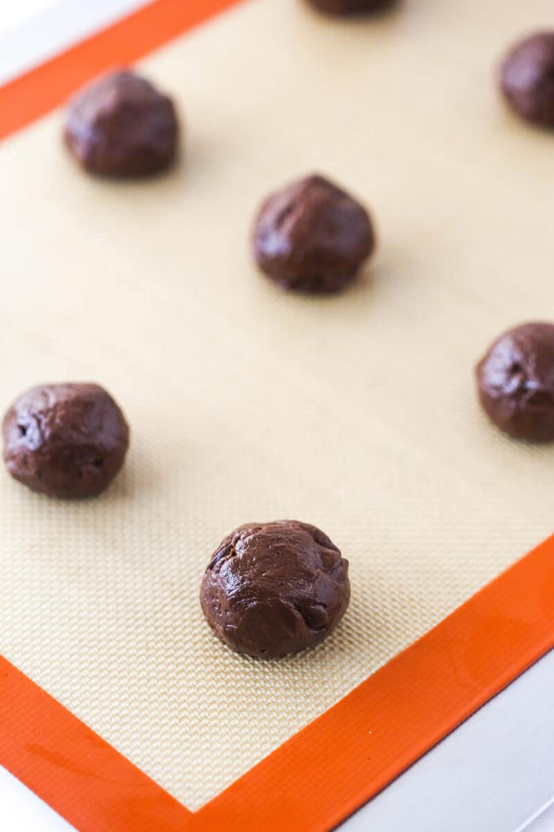 Brownie cookie dough balls on a silicon baking mat.