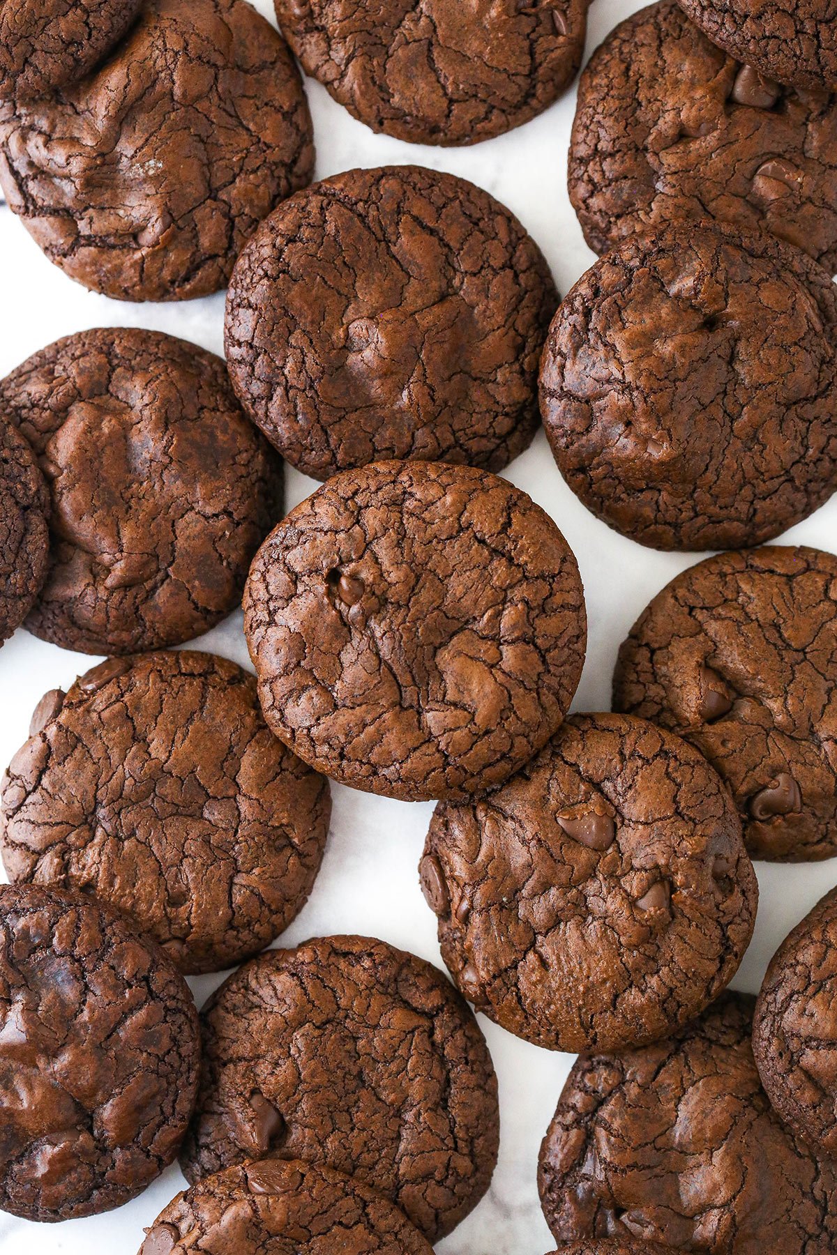 Overhead image of brownie cookies scattered on a marble surface.