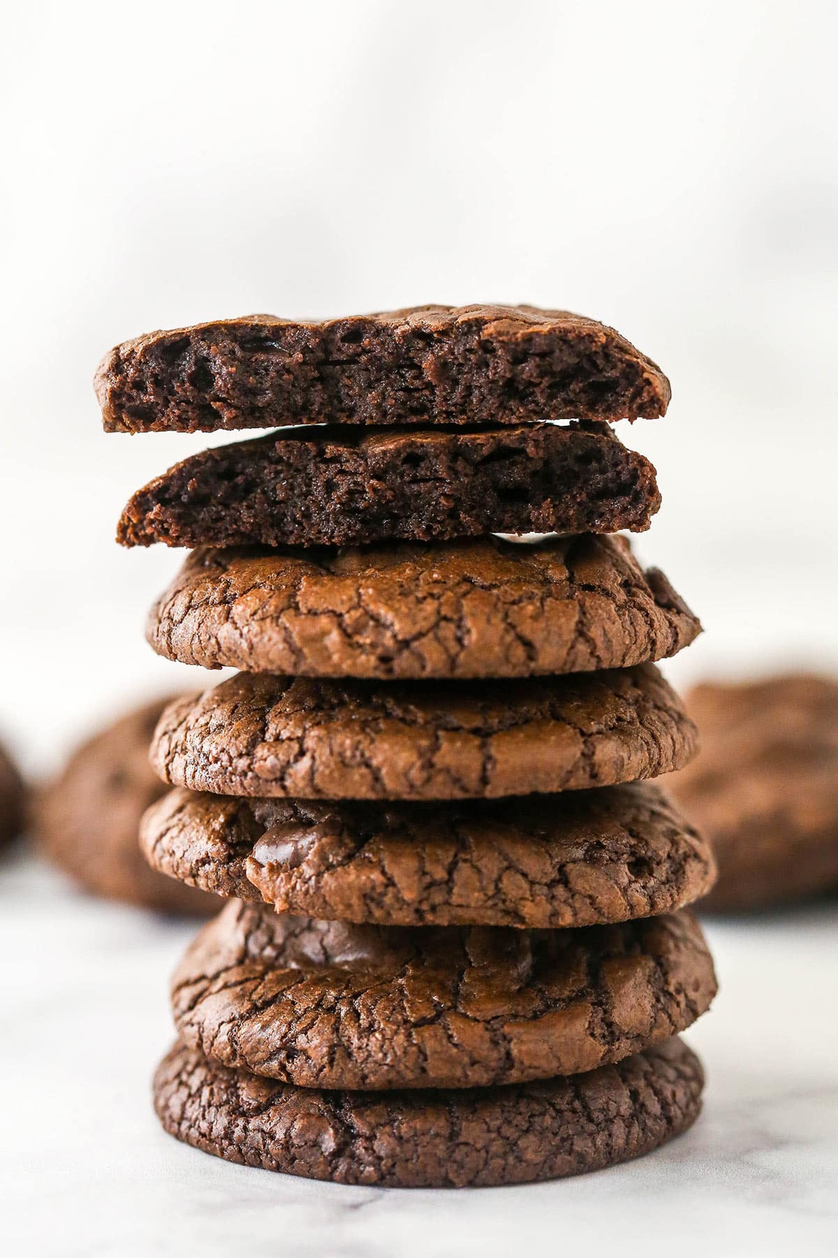 A stack of brownie cookies. The top one is broken in half.