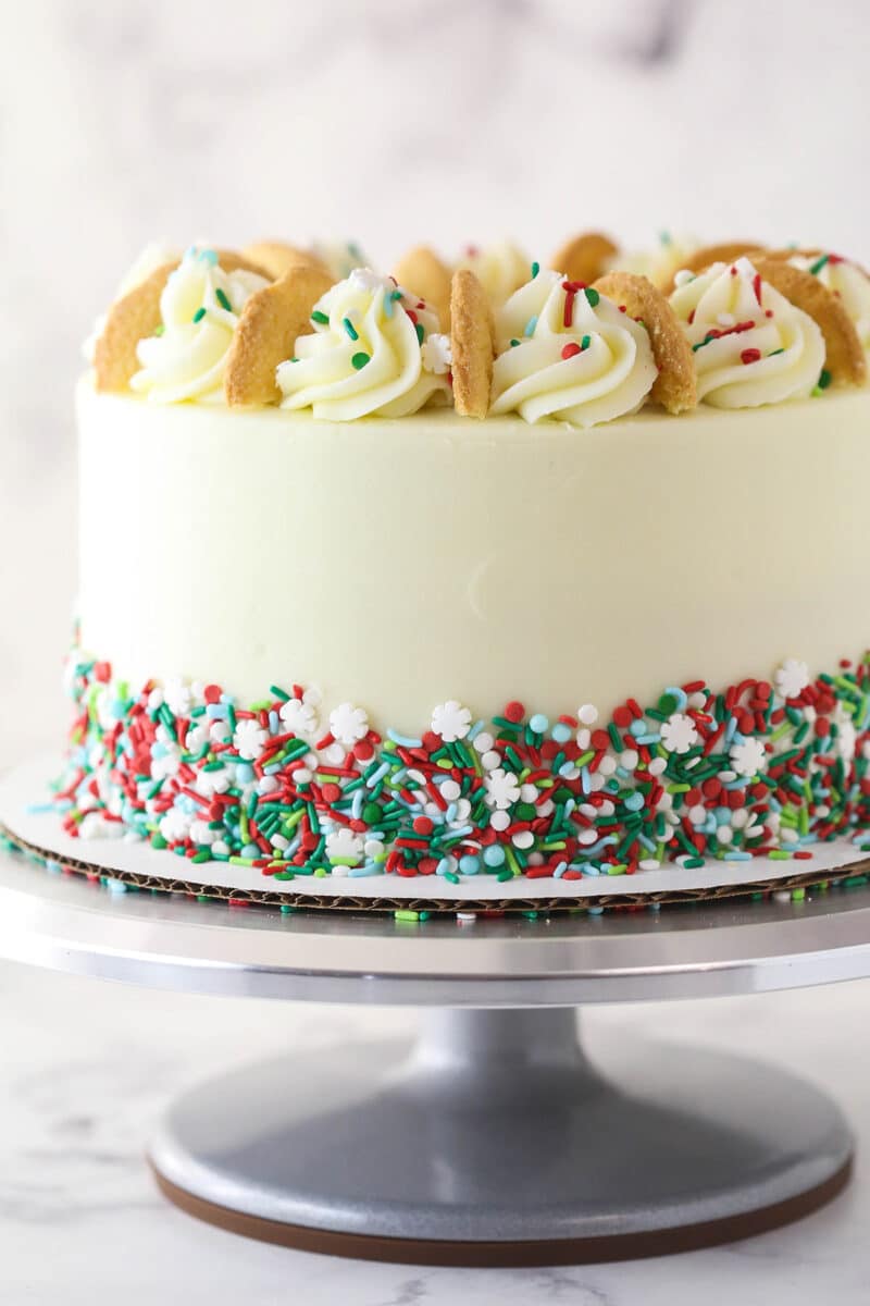A Frosted Sugar Cookie Layer Cake on a silver cake plate.