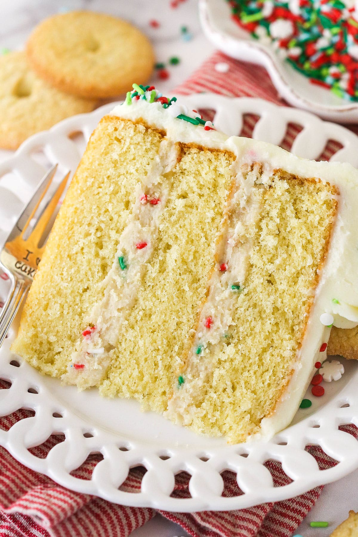 A slice of Frosted Sugar Cookie Layer Cake on a small white plate.