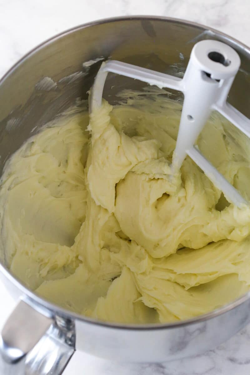 Cream cheese and sugar creamed together in a metal mixing bowl.