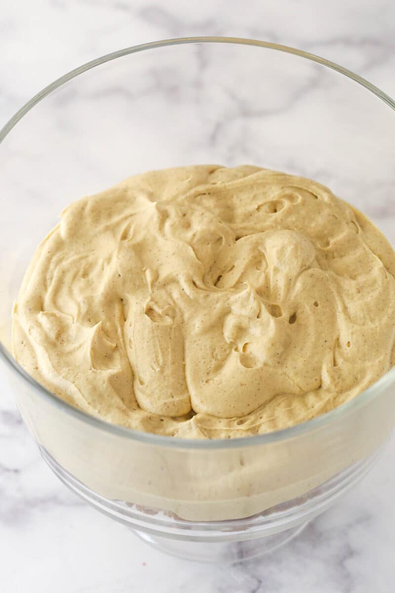 A glass trifle bowl with a layer of gingerbread cheesecake filling.