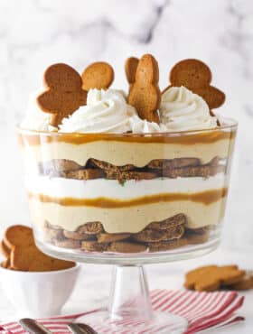 A Gingerbread Cheesecake Trifle in a trifle bowl on a striped napkin.