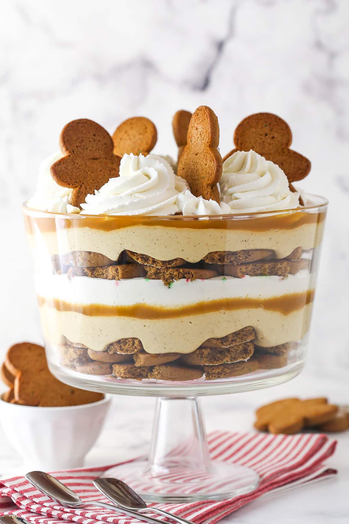 A Gingerbread Cheesecake Trifle in a trifle bowl on a striped napkin.