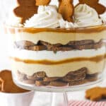 Close up of a Gingerbread Cheesecake Trifle in a trifle bowl on a striped napkin.