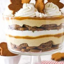 Close up of a Gingerbread Cheesecake Trifle in a trifle bowl on a striped napkin.