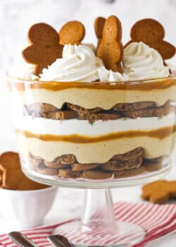 Close up of a Gingerbread Cheesecake Trifle in a trifle bowl on a striped napkin.