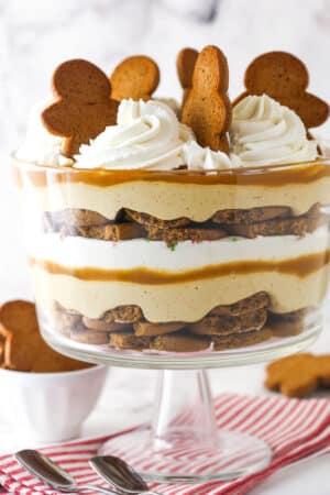 Close up of a Gingerbread Cheesecake Trifle in a trifle bowl on a striped napkin.