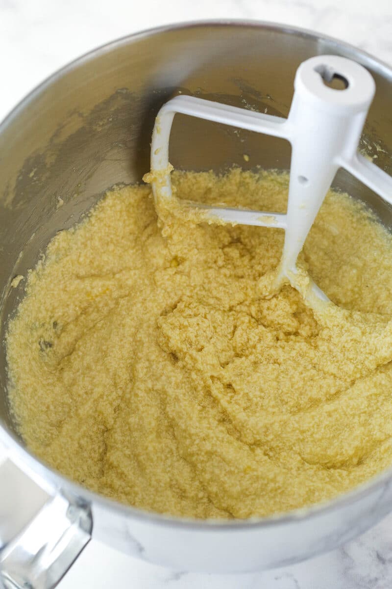 Mixing eggs and sour cream into creamed butter, sugar, and vanilla.