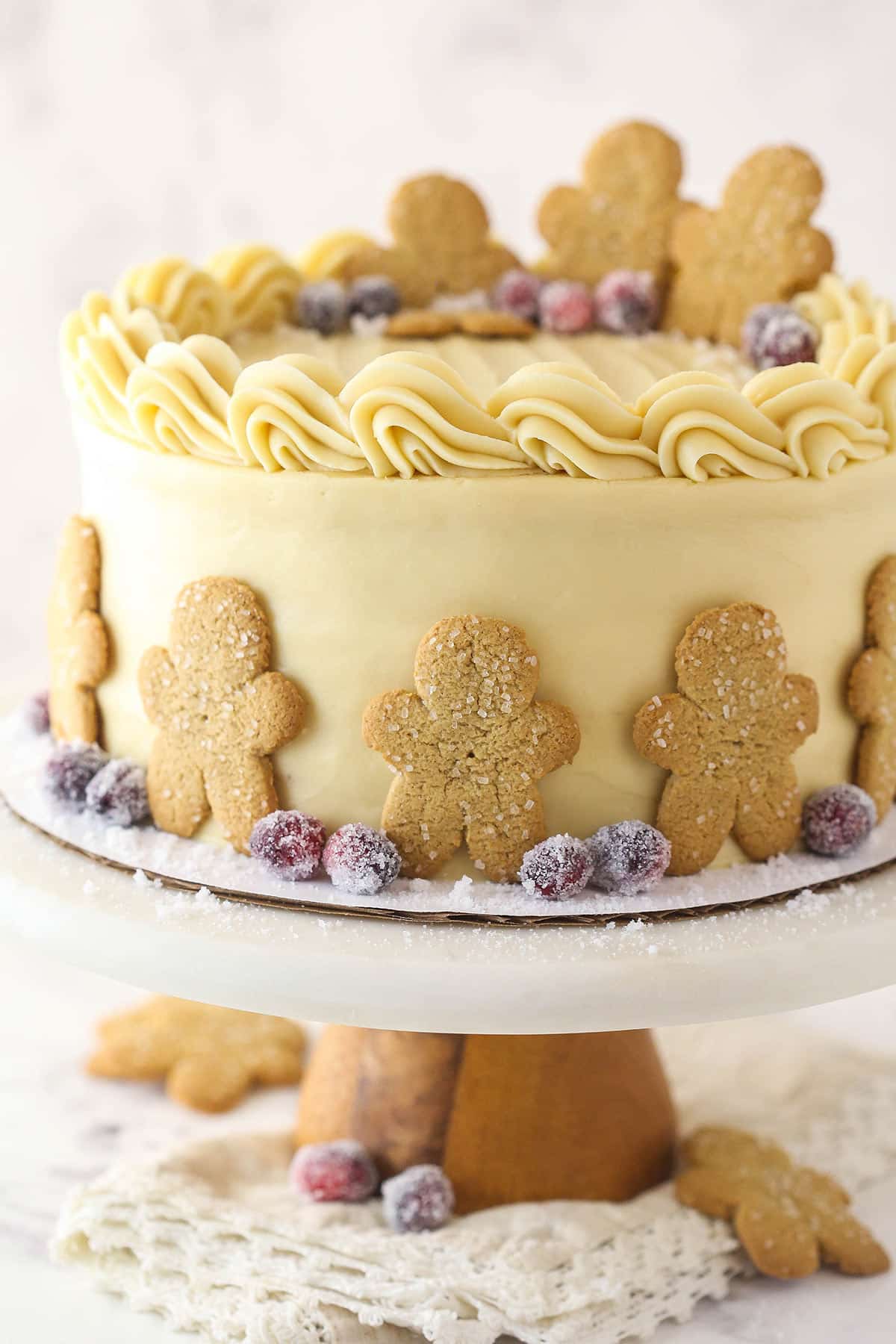 Gingerbread layer cake on a cake stand garnished with gingerbread men and sugared cranberries.