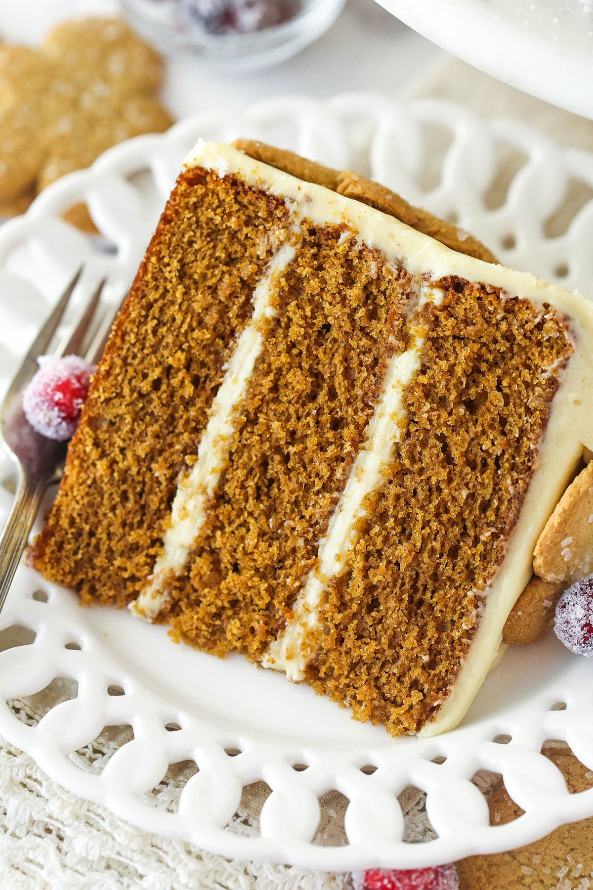 A slice of gingerbread layer cake on a plate with a fork.