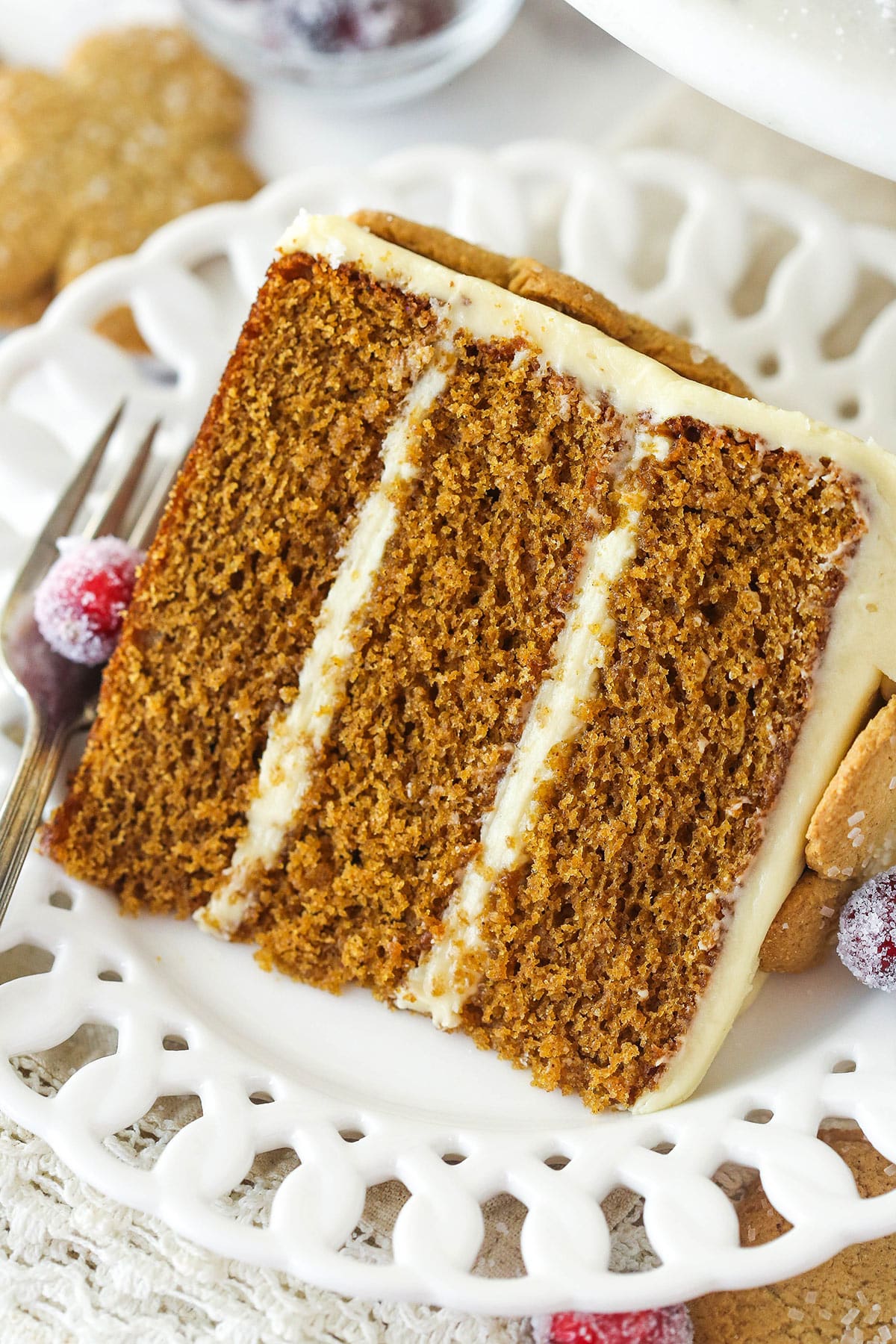 This gingerbread layer cake is made of 3 moist cake layers loaded with gingerbread flavor and frosted with a smooth molasses cream cheese frosting. A slice of gingerbread layer cake on a plate with a fork.