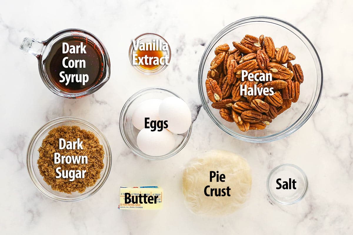 This pecan pie recipe features a luscious, buttery filling loaded with pecans & bursting with the rich flavors of dark brown sugar & vanilla. Ingredients for Classic Pecan Pie with text labels.