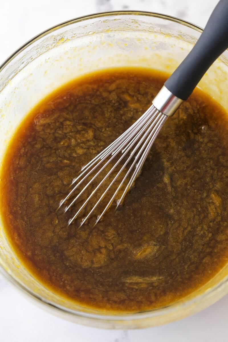 A mixing bowl with a mixture of eggs, dark corn syrup, dark brown sugar, vanilla, butter and salt.