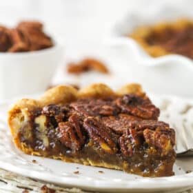 A slice of Classic Pecan Pie on a white plate.
