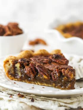 A slice of Classic Pecan Pie on a white plate.