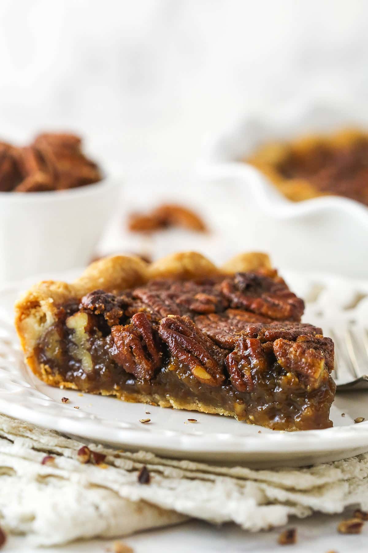 A slice of Classic Pecan Pie on a white plate.