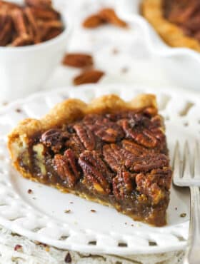 A slice of Classic Pecan Pie in a white plate next to a fork.