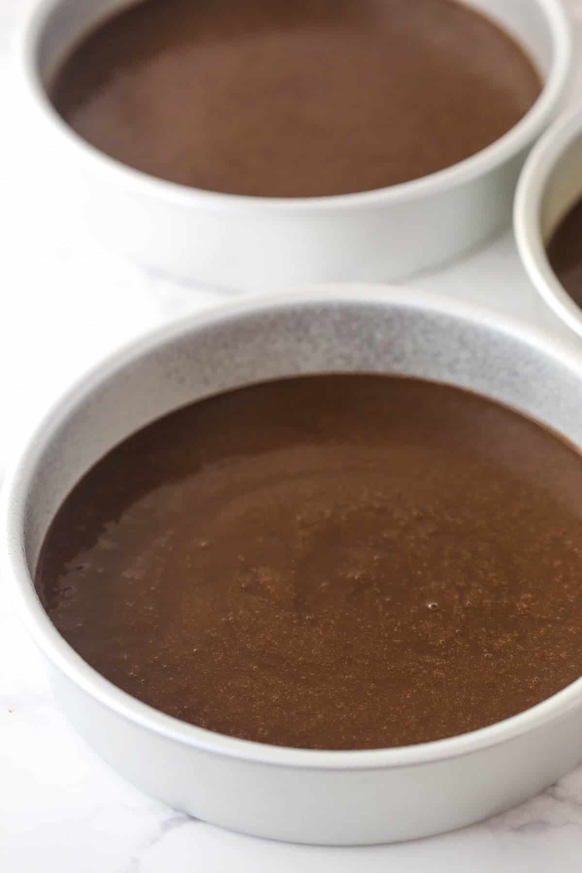 Chocolate cake batter in cake pans ready to be baked.