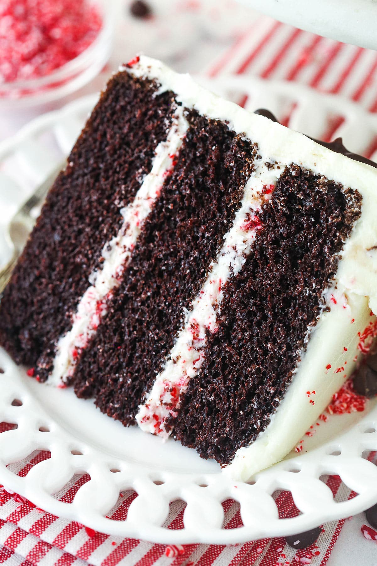 Chocolate peppermint cake is made of layers of chocolate cake frosted with peppermint buttercream and finished with chocolate ganache. A slice of chocolate peppermint layer cake on a plate.