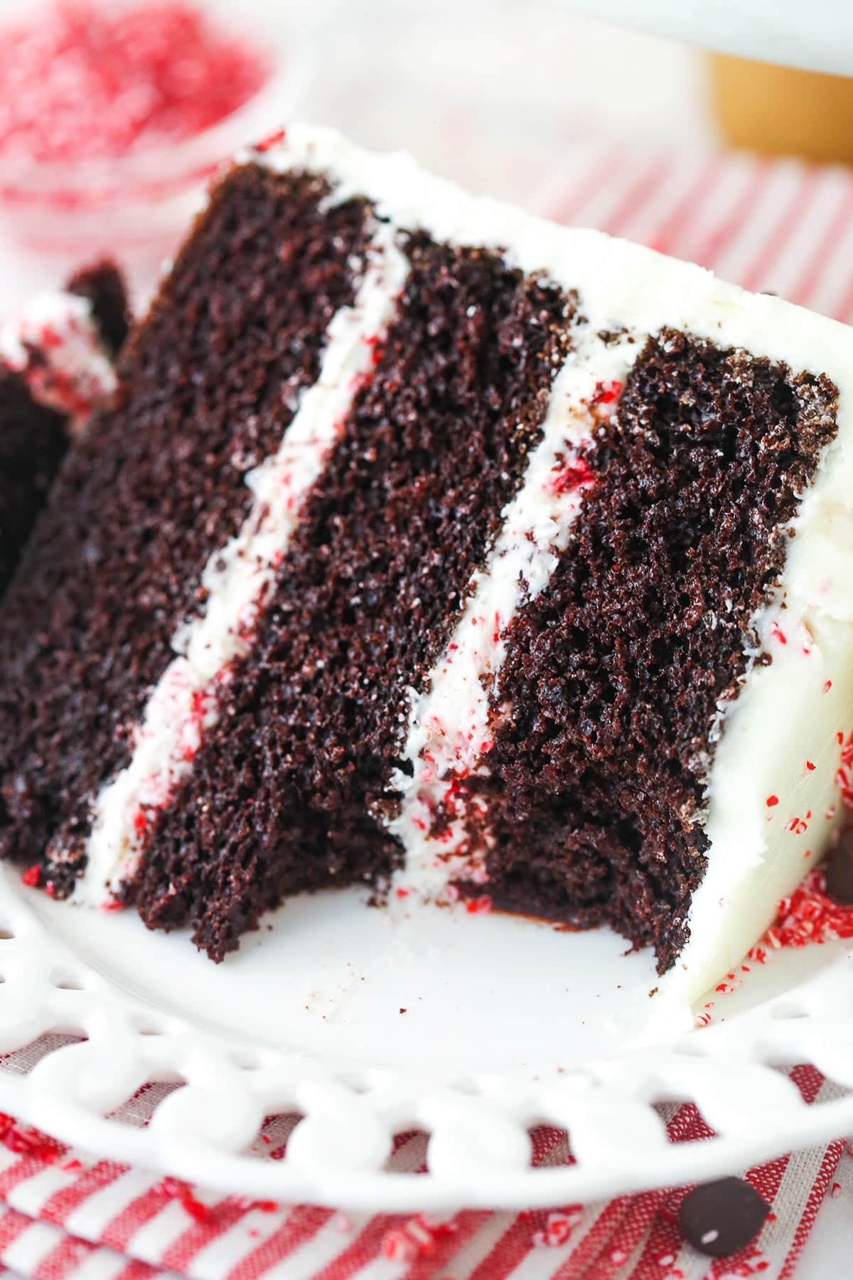 A slice of chocolate peppermint layer cake on a plate with a bite taken out of it.