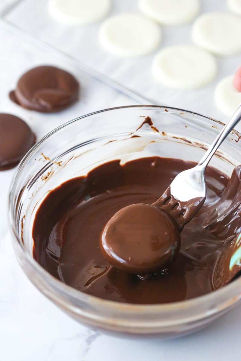 Dipping peppermint patties in chocolate.