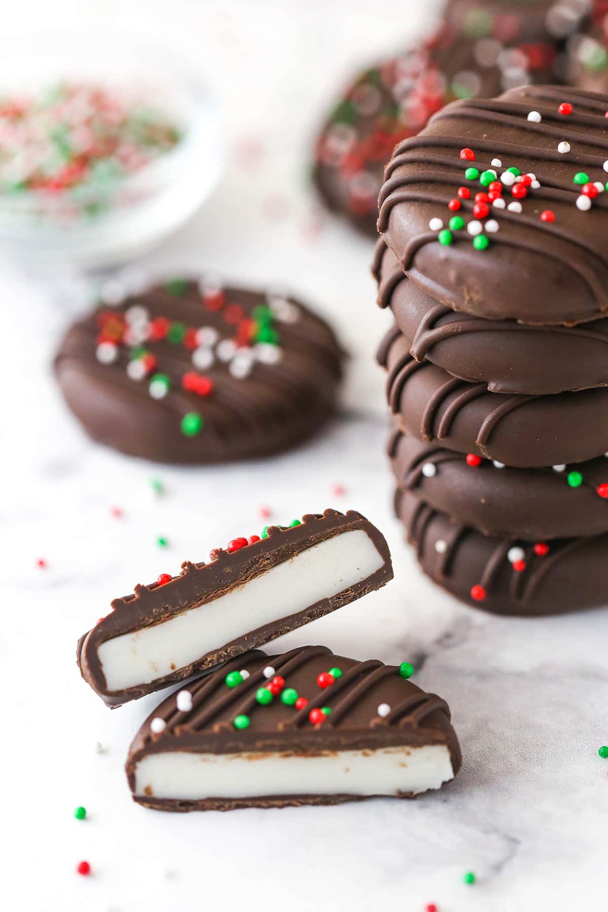 A peppermint patty broken in half near a stack of peppermint patties.