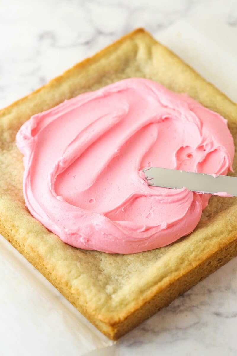 Spreading pick frosting over sugar cookie bars.