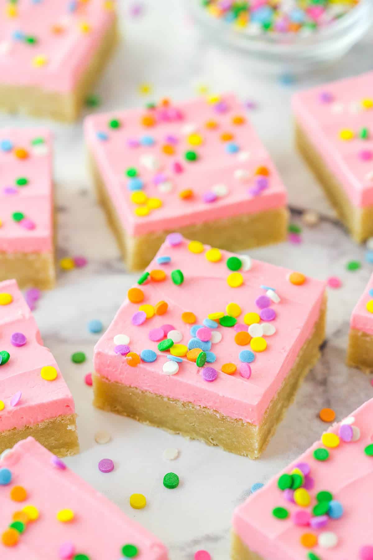 Sugar cookie bars with sprinkles on a marble countertop.