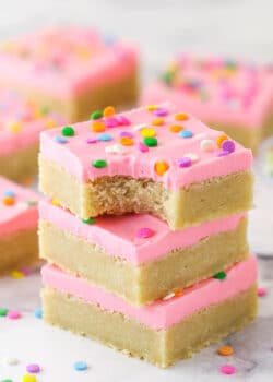 A stack of sugar cookie bars. The top one has a bite taken out of it.