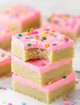A stack of sugar cookie bars. The top one has a bite taken out of it.