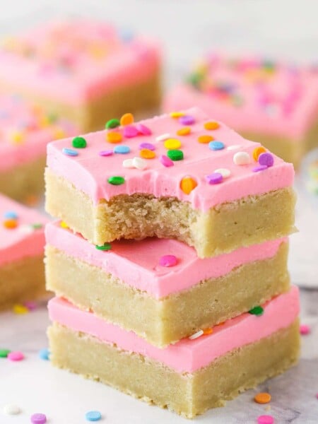 A stack of sugar cookie bars. The top one has a bite taken out of it.