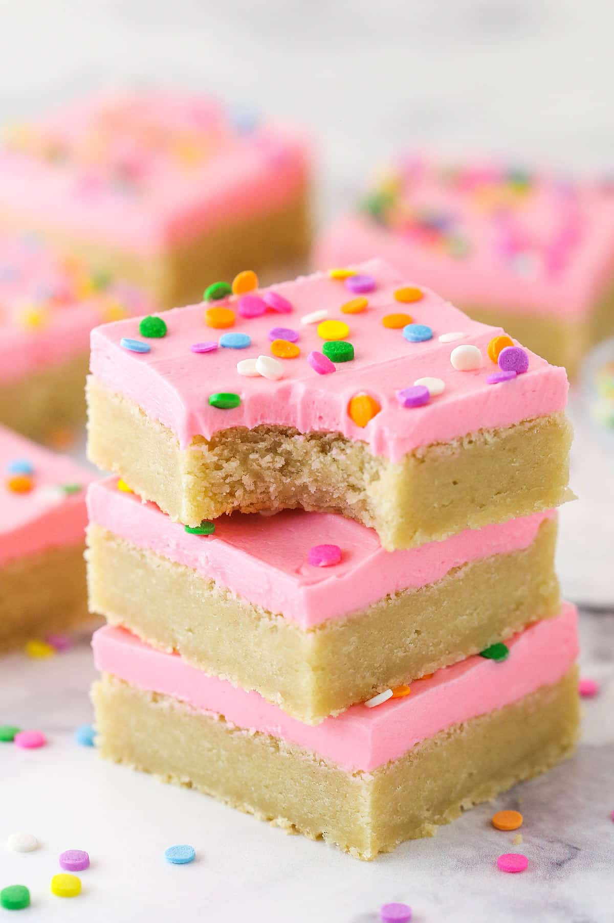 A stack of sugar cookie bars. The top one has a bite taken out of it.